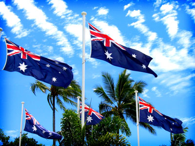 Half a dozen Australian flags flying cheerily in breeze; palm trees nearby