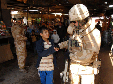 British soldier guarding market shakes hand of smiling boy