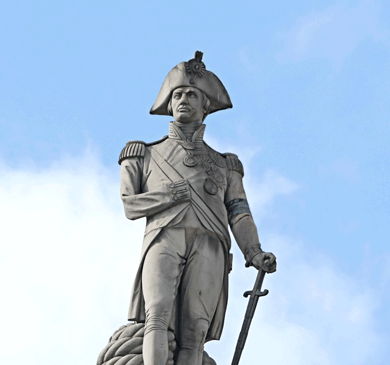 Statue of Horatio Nelson shows him dressed in naval uniform. Due to war injuries he is missing his right hand and blind in one eye. 