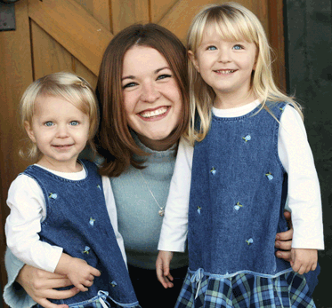 smililng mother with two little daughters