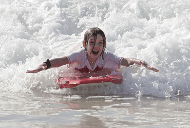 Young girl surfing in ocean