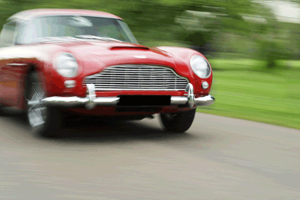 Old red Aston Martin racing into country