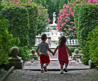 Two children walking hand in hand into a garden